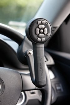 Lollypop style hand control handle with control pad installed on a steering wheel.